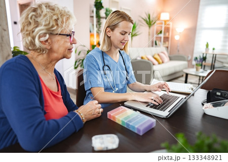 Caring interaction between a nurse and a senior woman in a cozy home setting 133348921