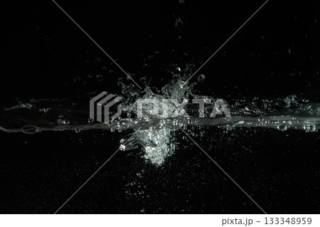 Water splashing as it's poured into aquarium tank, black background 133348959