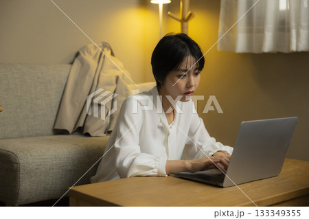 夜リビングでパソコンを見る若い女性 夜リビングでパソコンを見る若い女性 133349355