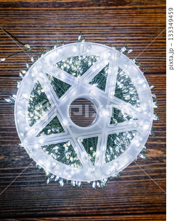 Garland glows with white light on a brown wooden background. 133349459
