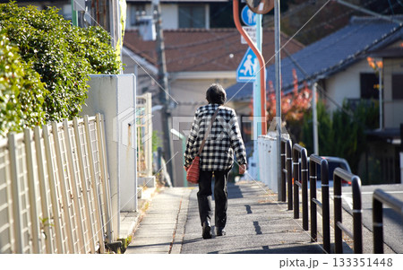 秋の朝の住宅街で歩くシニア女性の姿 秋の朝の住宅街で歩くシニア女性の姿 133351448