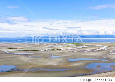 Wide sandy beach at low tide with tidepools in sunny day. Wide sandy beach at low tide with tidepools in sunny day. 133351853