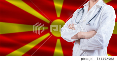 Doctor with crossed arms on North Macedonia flag. North Macedonia health and care concept. Female doctor on North Macedonia flag Doctor with crossed arms on North Macedonia flag. North Macedonia health and care concept. Female doctor on North Macedonia flag 133352568