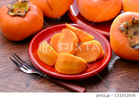 秋の日本の果物、柿（カキ）。背景のもみじ（紅葉）は造花です。 133352636