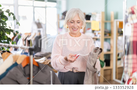Focused european mature woman choose hat for winter season in clothing outlet store 133352928