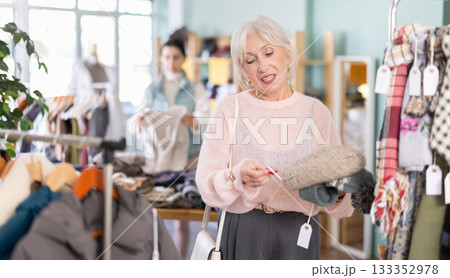 Focused european mature woman choose hat for winter season in clothing outlet store 133352978