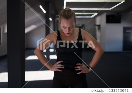 Woman taking a break after an intense workout in a modern fitness studio showing determination and focus on her fitness journey Woman taking a break after an intense workout in a modern fitness studio showing determination and focus on her fitness journey 133353041