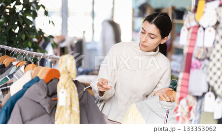 Woman chooses coat or jacket for the winter period in a fashionable clothing store Woman chooses coat or jacket for the winter period in a fashionable clothing store 133353062