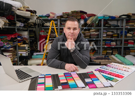 Tailor or designer in his workshop with fabric samples, looking at fabric swatches and laptop, textile industry, small business owner, entrepreneur, fashion design studio. 133353306