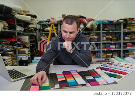 Man selecting fabric swatches in textile warehouse, designer choosing colors, material samples for fashion design, tailor at work, fabric store, textile industry Man selecting fabric swatches in textile warehouse, designer choosing colors, material samples for fashion design, tailor at work, fabric store, textile industry 133353372