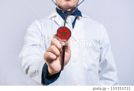 Healthcare worker holding stethoscope with Morocco flag. Morocco health and care concept Healthcare worker holding stethoscope with Morocco flag. Morocco health and care concept 133353721