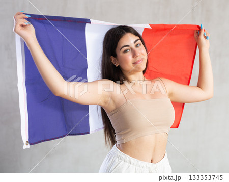 Happy young woman with flag of France against unicoloured background Happy young woman with flag of France against unicoloured background 133353745