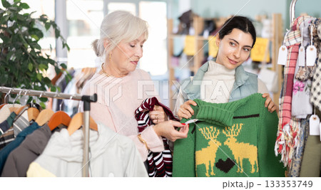 Two customers are choosing sweaters with interest Two customers are choosing sweaters with interest 133353749
