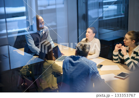 Diverse business team gathered around a table discussing analytics during a meeting in a modern office. Laptop screen shows charts and graphs, symbolizing teamwork, communication, and data driven Diverse business team gathered around a table discussing analytics during a meeting in a modern office. Laptop screen shows charts and graphs, symbolizing teamwork, communication, and data driven 133353767