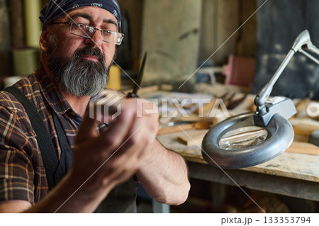 Artisan woodworker carving wood with knife in workshop, craftsman carefully shaping wood with hand tools, hobbyist creating handmade crafts, woodworking project in studio. Artisan woodworker carving wood with knife in workshop, craftsman carefully shaping wood with hand tools, hobbyist creating handmade crafts, woodworking project in studio. 133353794