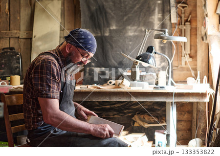 Craftsman sanding wood in workshop, woodworking project, artisan focused on handmade craft, skilled worker creating wooden object, carpentry in rustic environment, hobbyist at work 133353822