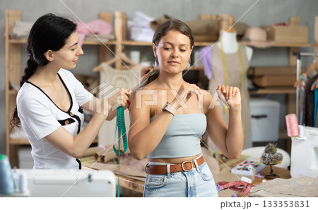 dressmaker takes measurements from the client 133353831