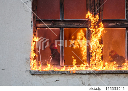 Firefighter rescuing a baby from burning building, fireman in action saving child, emergency situation, fire in house, danger, rescue operation, outdoor scene 133353943
