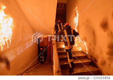Firefighters in action, climbing stairs amidst flames and smoke, showcasing bravery and emergency response in a building fire situation, interior scene, danger, rescue. Firefighters in action, climbing stairs amidst flames and smoke, showcasing bravery and emergency response in a building fire situation, interior scene, danger, rescue. 133353958