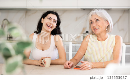 Young woman and elderly woman drinking tea in kitchen 133353987