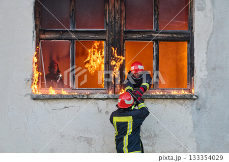 Firefighter rescuing a baby from burning building, fireman in action saving child, emergency situation, fire in house, danger, rescue operation, outdoor scene Firefighter rescuing a baby from burning building, fireman in action saving child, emergency situation, fire in house, danger, rescue operation, outdoor scene 133354029