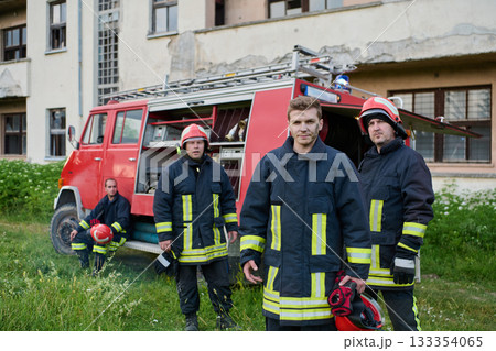 Firefighters in uniform and helmets posing in front of fire truck, emergency service team, rescue operation, fire safety, urban scene, outdoor, teamwork and bravery concept Firefighters in uniform and helmets posing in front of fire truck, emergency service team, rescue operation, fire safety, urban scene, outdoor, teamwork and bravery concept 133354065