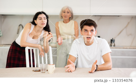 Upset and unhappy son-in-law sitting in the kitchen separately, family conflict 133354076