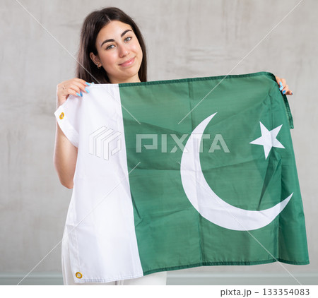 Happy young woman with flag of Pakistan against unicoloured background Happy young woman with flag of Pakistan against unicoloured background 133354083