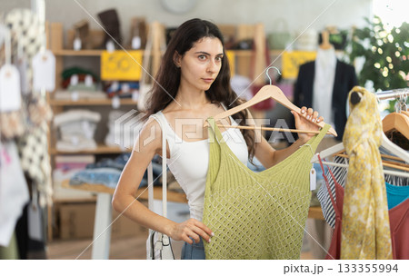 Woman on sale choosing dresses and tops in the store Woman on sale choosing dresses and tops in the store 133355994