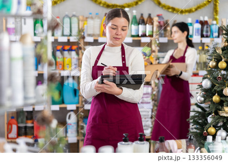 Female seller with tablet, plans to replenish restock stores inventory, colleague in background 133356049