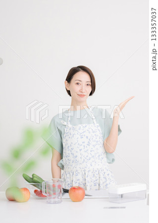 エプロン姿の主婦がキッチンで野菜料理を準備しオススメや紹介の笑顔の女性 家庭のダイエットや健康 エプロン姿の主婦がキッチンで野菜料理を準備しオススメや紹介の笑顔の女性 家庭のダイエットや健康 133357037