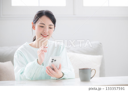 スマホ持つ女性が笑顔で幸せ感じる室内のかわいい日本人 問い合わせなどで考える よくある質問のイメージ スマホ持つ女性が笑顔で幸せ感じる室内のかわいい日本人 問い合わせなどで考える よくある質問のイメージ 133357591