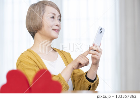 スマホでマッチングアプリをするシニア女性 133357862