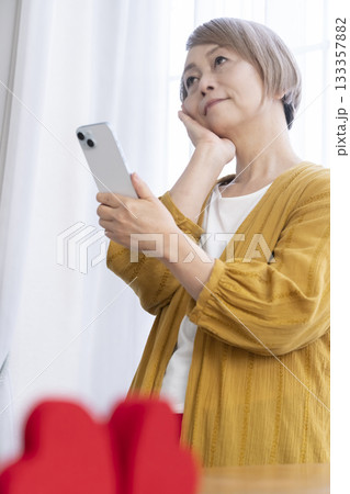 スマホでマッチングアプリをするシニア女性 133357882