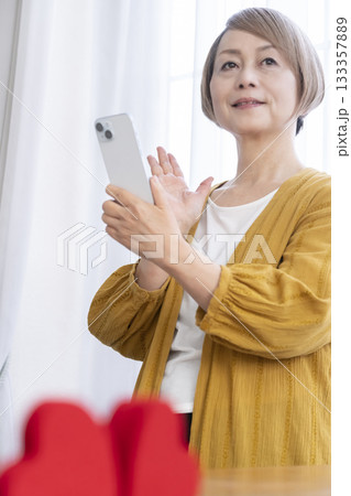 スマホでマッチングアプリをするシニア女性 133357889