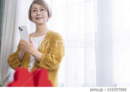 スマホでマッチングアプリをするシニア女性 スマホでマッチングアプリをするシニア女性 133357892