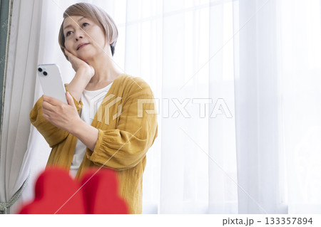 スマホでマッチングアプリをするシニア女性 スマホでマッチングアプリをするシニア女性 133357894