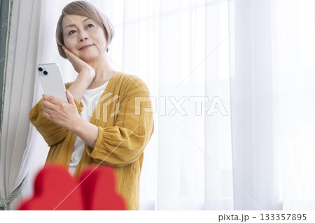 スマホでマッチングアプリをするシニア女性 スマホでマッチングアプリをするシニア女性 133357895
