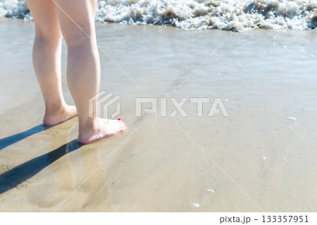 海辺を歩く若い女性　白い波　快晴　シーサイド　素足　美しい　理想　休日　バカンス　ビーチ　女性 133357951