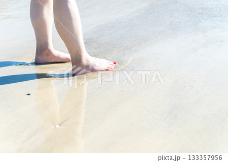 海辺を歩く若い女性　白い波　快晴　シーサイド　素足　美しい　理想　休日　バカンス　ビーチ　女性 133357956
