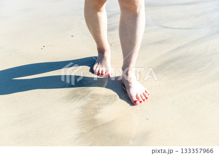 海辺を歩く若い女性　白い波　快晴　シーサイド　素足　美しい　理想　休日　バカンス　ビーチ　女性 133357966