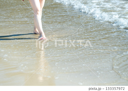 海辺を歩く若い女性　白い波　快晴　シーサイド　素足　美しい　理想　休日　バカンス　ビーチ　女性 133357972