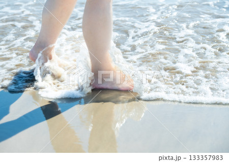 海辺を歩く若い女性　白い波　快晴　シーサイド　素足　美しい　理想　休日　バカンス　ビーチ　女性 133357983