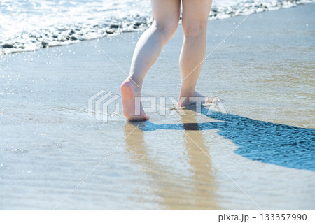 海辺を歩く若い女性　白い波　快晴　シーサイド　素足　美しい　理想　休日　バカンス　ビーチ　女性 133357990