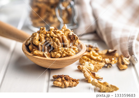 Peeled walnut kernels on wooden spoon on white table. Peeled walnut kernels on wooden spoon on white table. 133359683