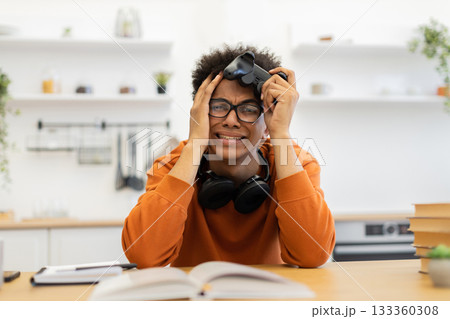 A young man with glasses is visibly frustrated while holding a game controller. A young man with glasses is visibly frustrated while holding a game controller. 133360308