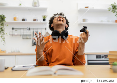 A young man wearing glasses is visibly frustrated while holding a game controller, likely after a loss. 133360368