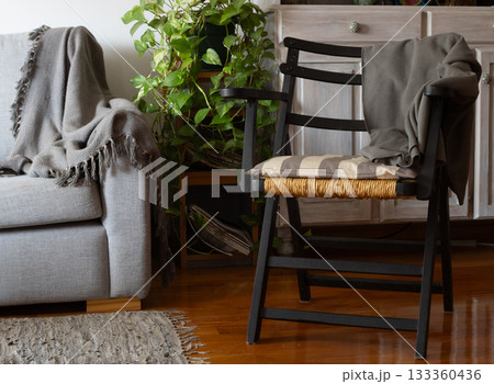 Cozy living space creating a hygge ambiance with warm candlelight, rustic furniture, comfortable throw blanket, and woven natural textures in a stylish home interior 133360436