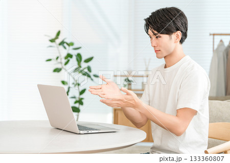 家のリビングでノートパソコンを使う若いアジア人男性（Web会議,オンライン会議,リモートワーク） 133360807