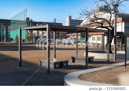 体育館の前にある運動場の屋根付き無人のベンチ 133360885